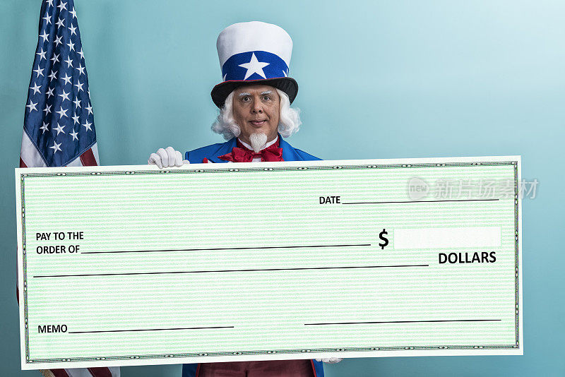 山姆大叔拿着一张大支票，背靠蓝绿色的墙站着，概念-减税/退税